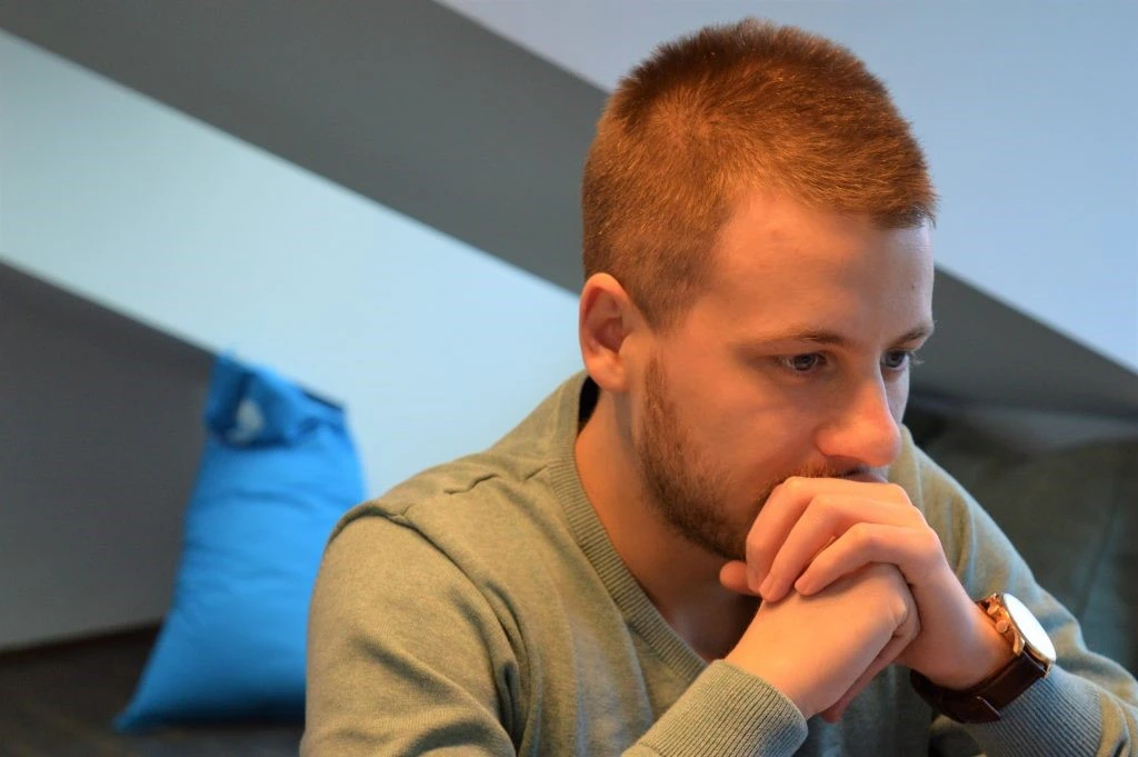 A person holding his hands together on his mouth while thinking 