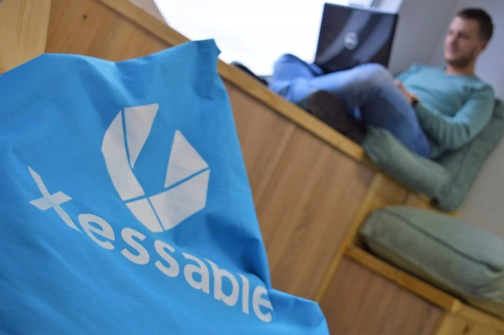 A company bean bag and a blurred background with a person working on a lap top